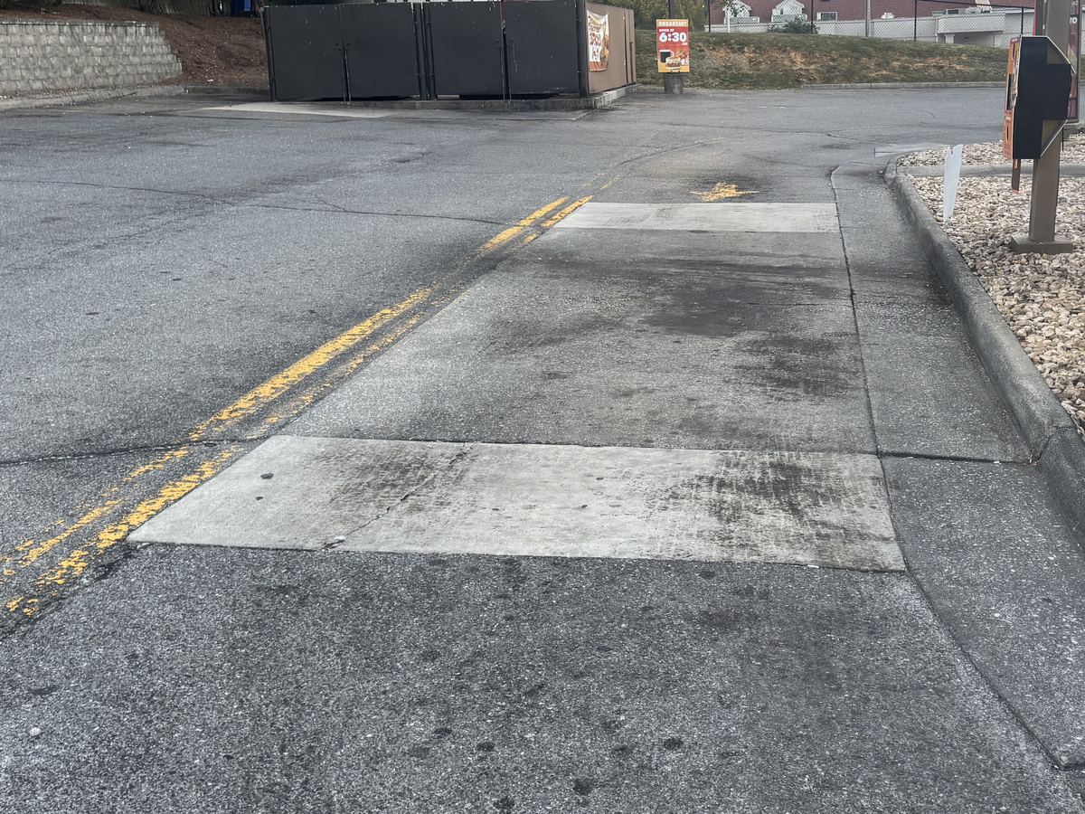 Stained concrete pad at a restaurant drive-thru before pressure washing