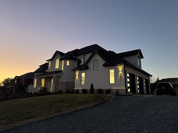Large new home at dusk with lights on